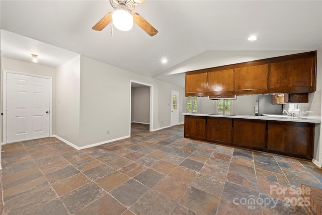 kitchen with stone tile flooring, baseboards, a ceiling fan, lofted ceiling, and a peninsula