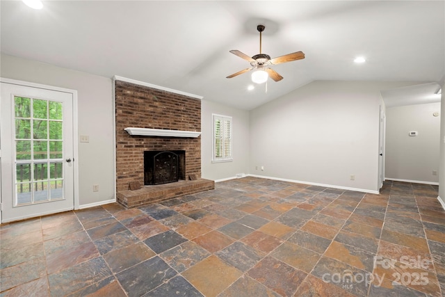 unfurnished living room with a ceiling fan, stone tile floors, baseboards, a fireplace, and lofted ceiling