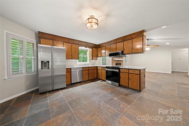 kitchen with appliances with stainless steel finishes, baseboards, brown cabinetry, light countertops, and recessed lighting