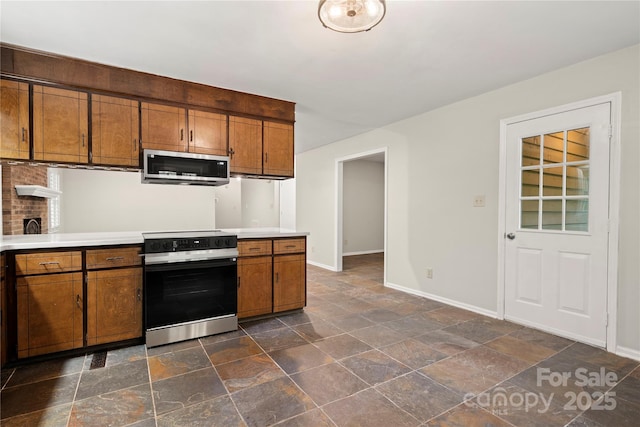 kitchen featuring range with electric stovetop, stainless steel microwave, and brown cabinetry