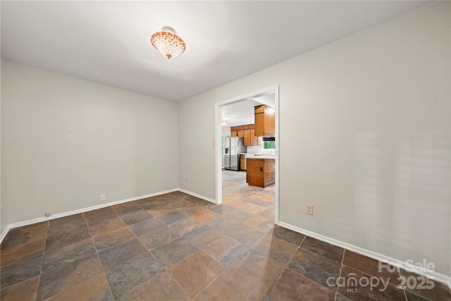 empty room featuring stone tile flooring and baseboards