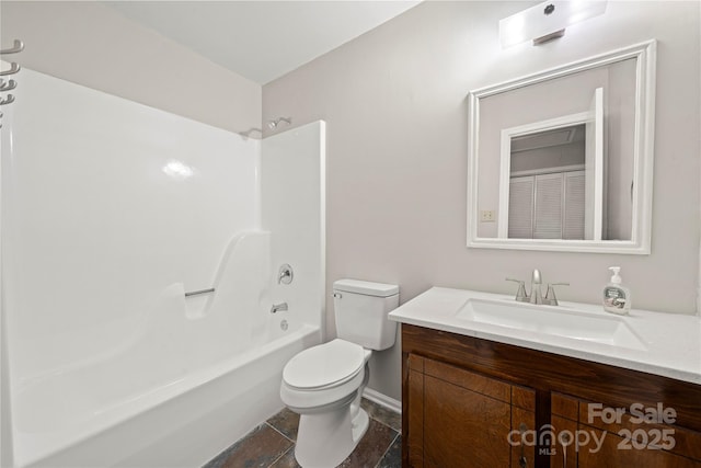 bathroom with toilet, vanity, shower / bathtub combination, and stone finish flooring