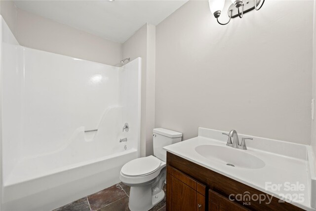 full bathroom with toilet, vanity, stone finish floors, and bathtub / shower combination