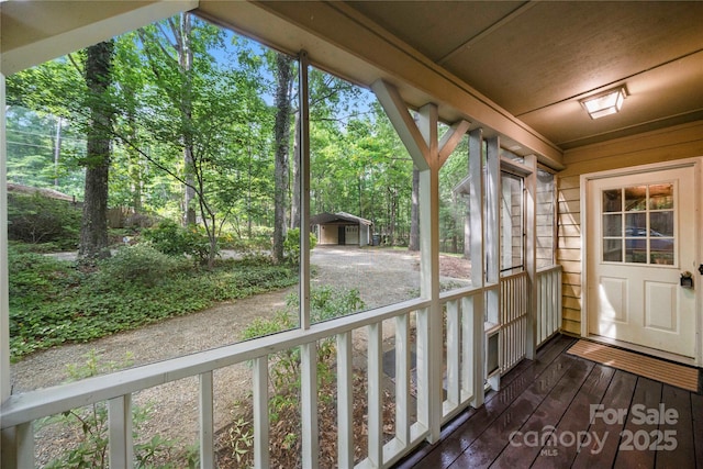unfurnished sunroom featuring view of wooded area and plenty of natural light