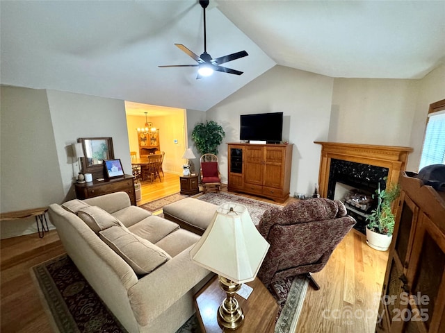 living area with wood finished floors, a chandelier, lofted ceiling, a ceiling fan, and a high end fireplace