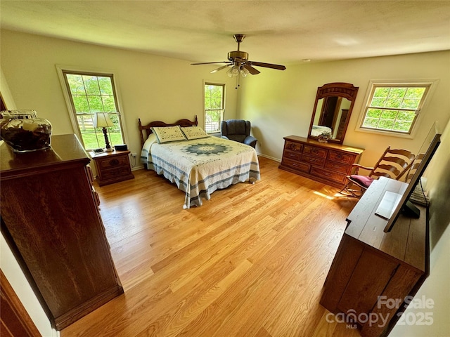 bedroom with light wood finished floors, multiple windows, and ceiling fan