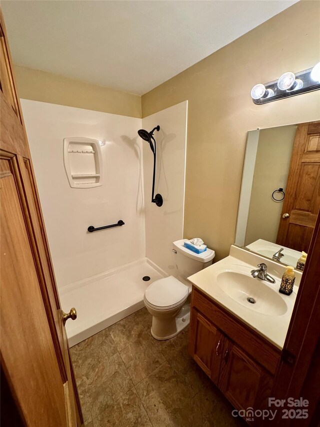 bathroom featuring a shower stall, toilet, and vanity