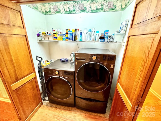 laundry area with washer and clothes dryer and light wood-style floors