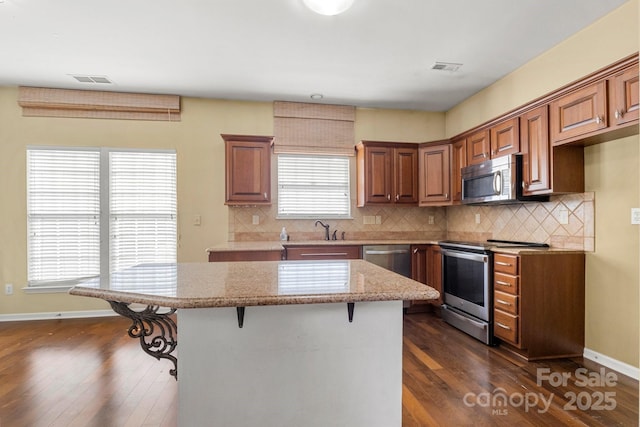 12824 Harvest Time Ct, Charlotte, NC 28278 - kitchen with stainless steel appliances, a center island, a breakfast bar, and dark wood-style flooring