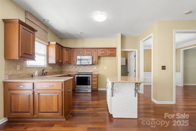 12824 Harvest Time Ct, Charlotte, NC 28278 - kitchen featuring appliances with stainless steel finishes, brown cabinetry, dark wood-type flooring, backsplash, and light stone countertops