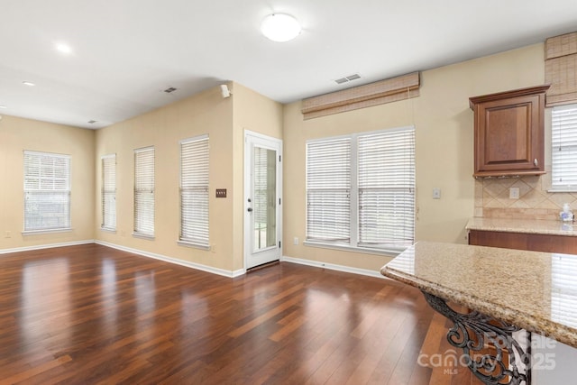 12824 Harvest Time Ct, Charlotte, NC 28278 - kitchen featuring light stone counters, dark wood-style floors, backsplash, baseboards, and recessed lighting