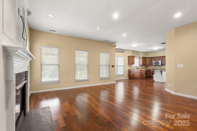 12824 Harvest Time Ct, Charlotte, NC 28278 - unfurnished living room featuring dark wood-style flooring, a fireplace with flush hearth, baseboards, recessed lighting, and a sink