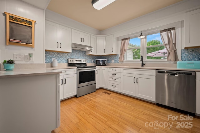 1761 Oak Grove Church Rd, Ellenboro, NC 28040 - kitchen featuring appliances with stainless steel finishes, under cabinet range hood, a sink, white cabinetry, and crown molding