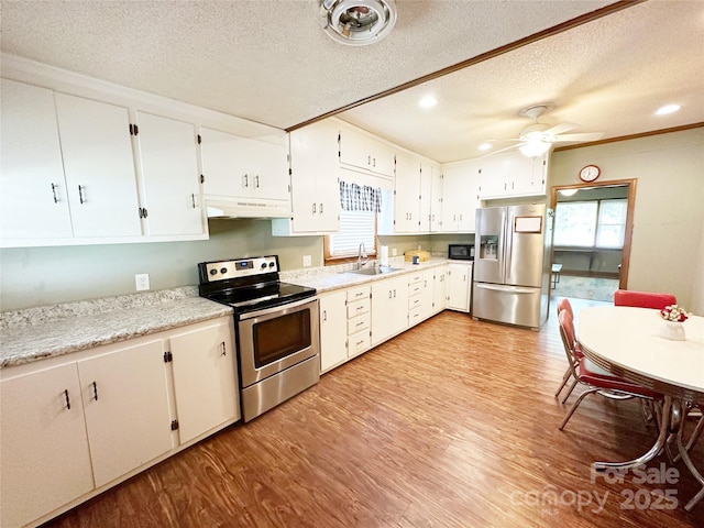 211 Spruce St, Badin, NC 28009 - kitchen with appliances with stainless steel finishes, under cabinet range hood, a sink, a textured ceiling, and light wood-type flooring