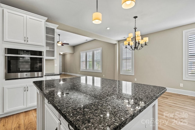 7362 Overjoyed Xing, Charlotte, NC 28215 - kitchen with stainless steel oven, light wood-style floors, a ceiling fan, a chandelier, and white cabinets