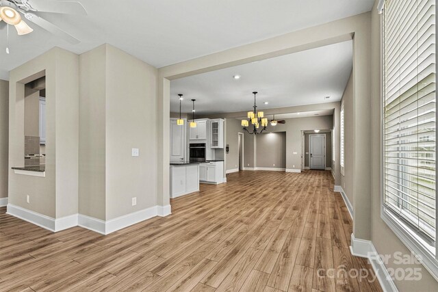 7362 Overjoyed Xing, Charlotte, NC 28215 - unfurnished living room featuring light wood-type flooring, a ceiling fan, a chandelier, and baseboards