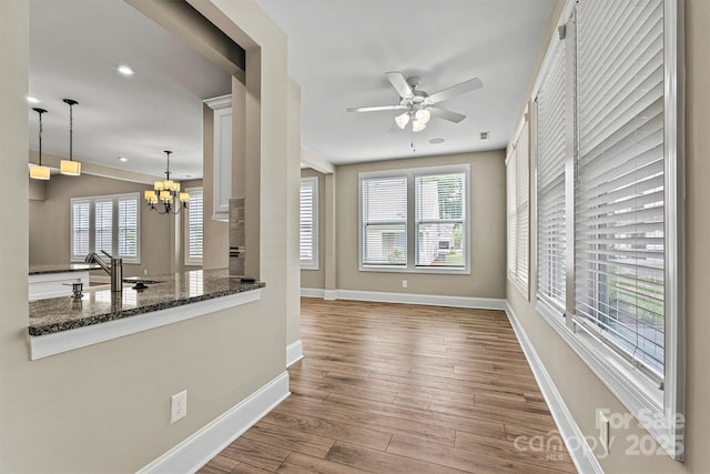 7362 Overjoyed Xing, Charlotte, NC 28215 - unfurnished living room featuring a chandelier, wood finished floors, a ceiling fan, baseboards, and a sink