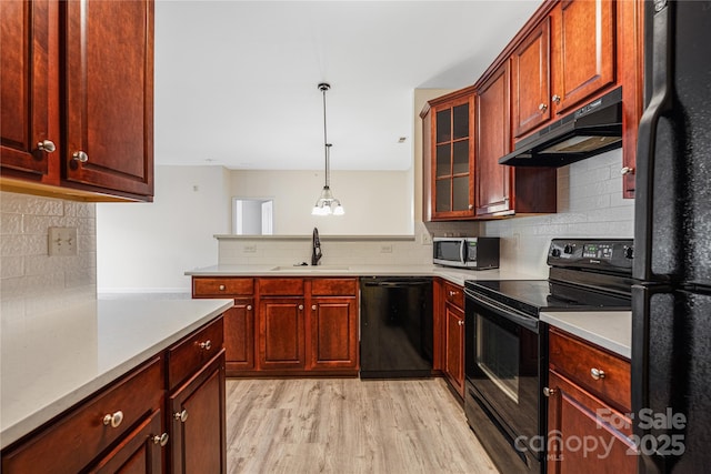 17111 Doe Valley Ct, Cornelius, NC 28031 - kitchen featuring black appliances, under cabinet range hood, decorative backsplash, a sink, and light wood-style floors