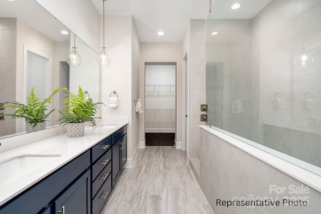 bathroom with walk in shower, a spacious closet, baseboards, double vanity, and marble finish floors