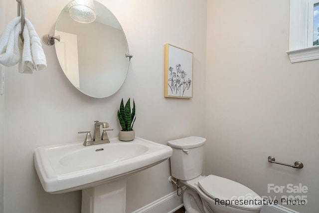 bathroom featuring toilet, a sink, and baseboards