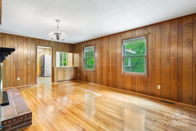 4306 Joplin Rd, Hudson, NC 28638 - unfurnished room with a chandelier, light wood finished floors, baseboards, wooden walls, and a textured ceiling