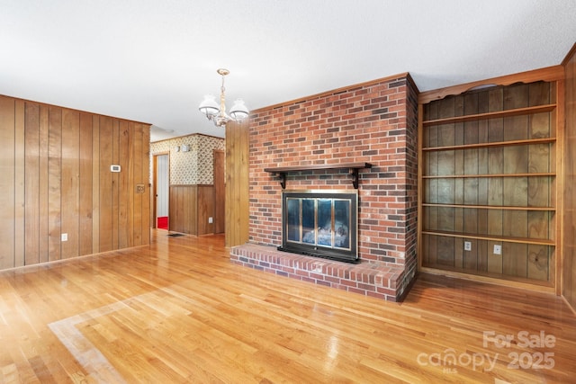 4306 Joplin Rd, Hudson, NC 28638 - unfurnished living room with wood finished floors, a chandelier, wood walls, and a brick fireplace