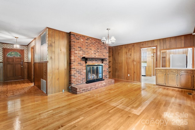 4306 Joplin Rd, Hudson, NC 28638 - unfurnished living room featuring a chandelier, wood walls, light wood-style flooring, and a fireplace