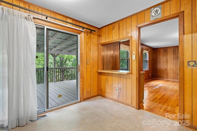 4306 Joplin Rd, Hudson, NC 28638 - empty room with wood walls, a textured ceiling, crown molding, tile patterned floors, and baseboards
