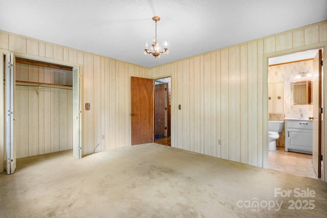 4306 Joplin Rd, Hudson, NC 28638 - unfurnished bedroom featuring light colored carpet, a chandelier, a closet, ensuite bathroom, and wooden walls