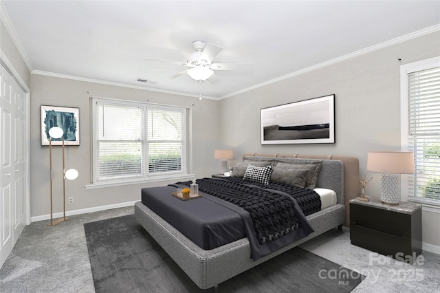 carpeted bedroom featuring baseboards, crown molding, ceiling fan, and a closet