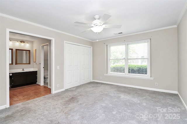 unfurnished bedroom with carpet flooring, baseboards, ornamental molding, a closet, and a sink