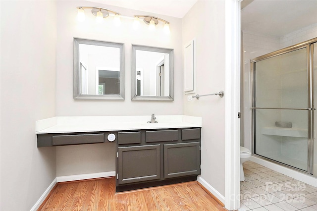 bathroom with toilet, a stall shower, vanity, and baseboards