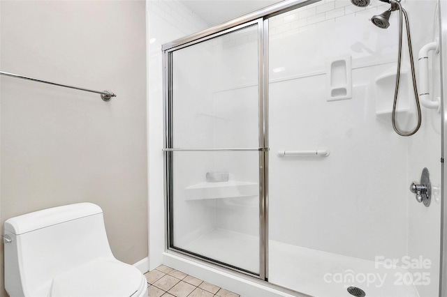 bathroom featuring a shower stall, tile patterned flooring, and toilet