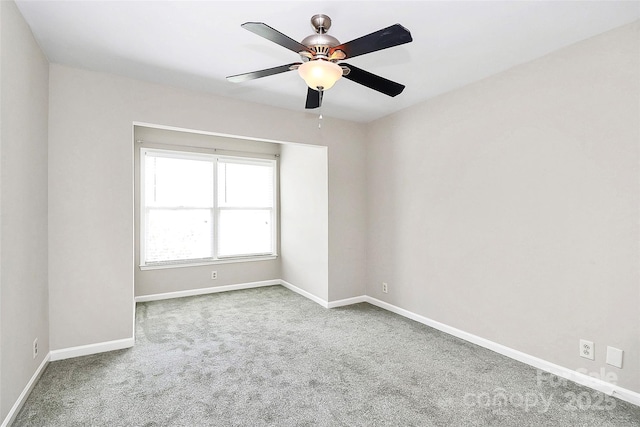 carpeted spare room with ceiling fan and baseboards