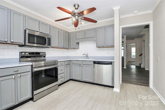 kitchen with stainless steel appliances, gray cabinets, ceiling fan, light countertops, and decorative backsplash