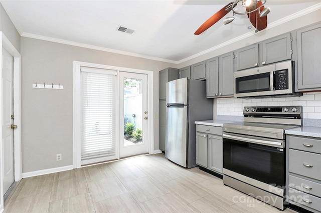 kitchen with gray cabinets, appliances with stainless steel finishes, ceiling fan, tasteful backsplash, and light countertops