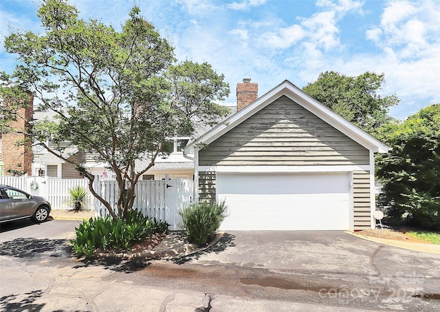 view of front of property featuring fence, a chimney, and a garage