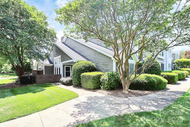 view of front facade with a front yard and roof with shingles