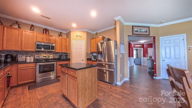 kitchen with appliances with stainless steel finishes, a center island, backsplash, dark wood finished floors, and crown molding