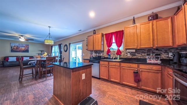 kitchen with stainless steel appliances, a kitchen island, dark wood-style flooring, a sink, and crown molding