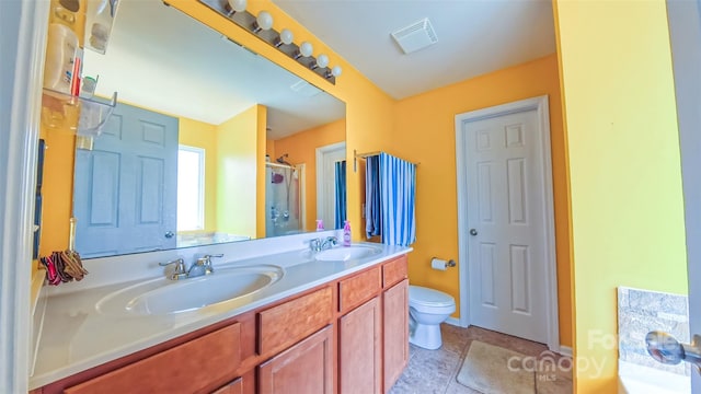 bathroom featuring a shower stall, double vanity, toilet, and tile patterned flooring
