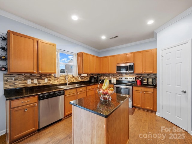 5003 Singletree Ln, Indian Trail, NC 28079 - kitchen featuring stainless steel appliances, light wood-type flooring, decorative backsplash, a center island, and ornamental molding