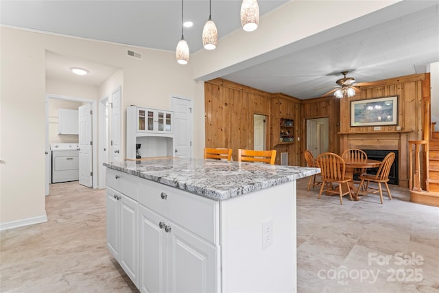 2315 Lanesboro Rd, Marshville, NC 28103 - kitchen featuring washer / dryer, wood walls, a ceiling fan, white cabinets, and light stone countertops
