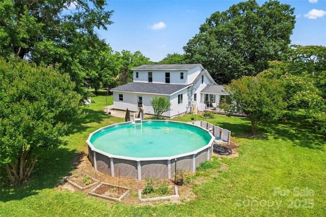 2315 Lanesboro Rd, Marshville, NC 28103 - back of house with a yard, roof with shingles, view of wooded area, and an outdoor pool