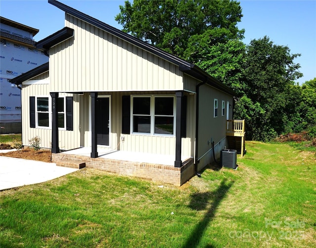 view of front of property with a front lawn, central air condition unit, a porch, and board and batten siding