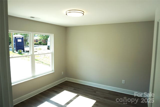 spare room with baseboards and dark wood-style floors