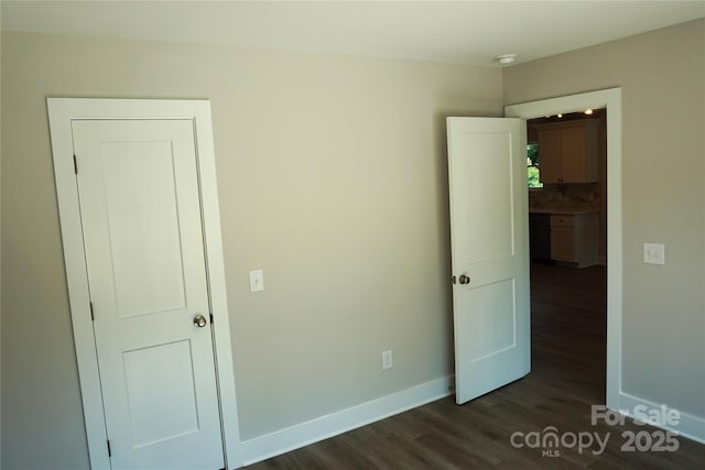 unfurnished bedroom with dark wood finished floors and baseboards