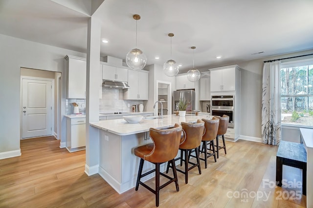 7513 Lancaster Hwy Unit 6, Waxhaw, NC 28173 - kitchen featuring appliances with stainless steel finishes, under cabinet range hood, light wood finished floors, a spacious island, and recessed lighting