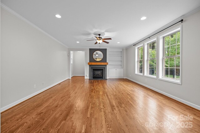 3206 Lakehurst Xing, Matthews, NC 28104 - unfurnished living room featuring ceiling fan, ornamental molding, built in shelves, baseboards, and a fireplace with flush hearth