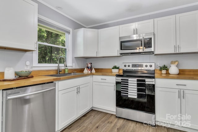 35 Avondale Rd, Asheville, NC 28803 - kitchen featuring appliances with stainless steel finishes, butcher block countertops, a sink, white cabinetry, and ornamental molding